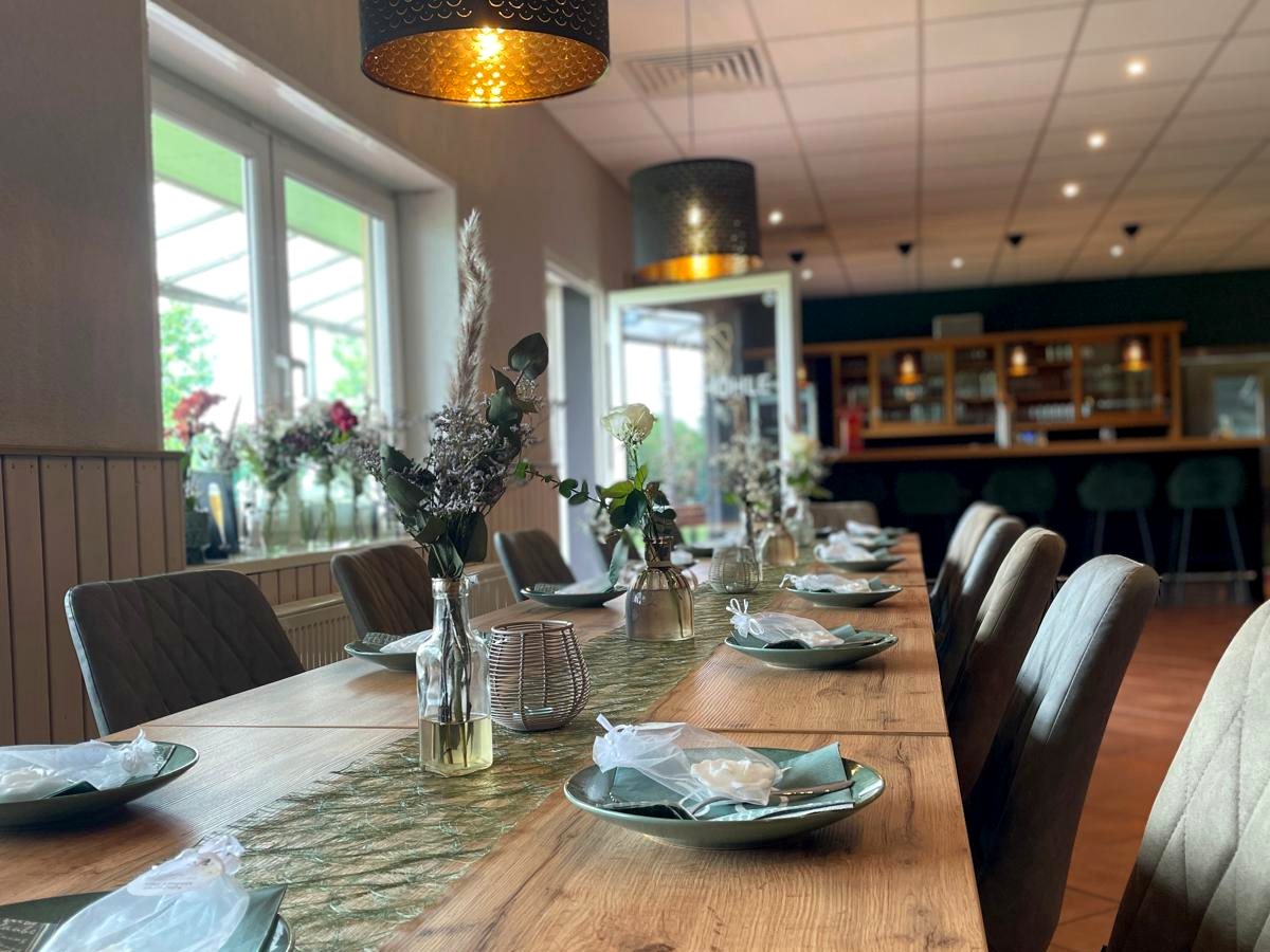 Gastraum mit eingedeckter Tafel und Bar im Hintergrund