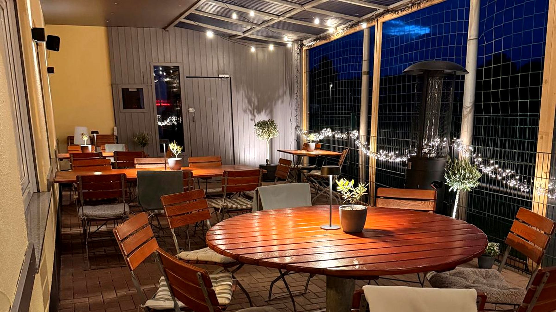 Überdachte Terrasse der Bärenhöhle am Abend mit Lichterketten